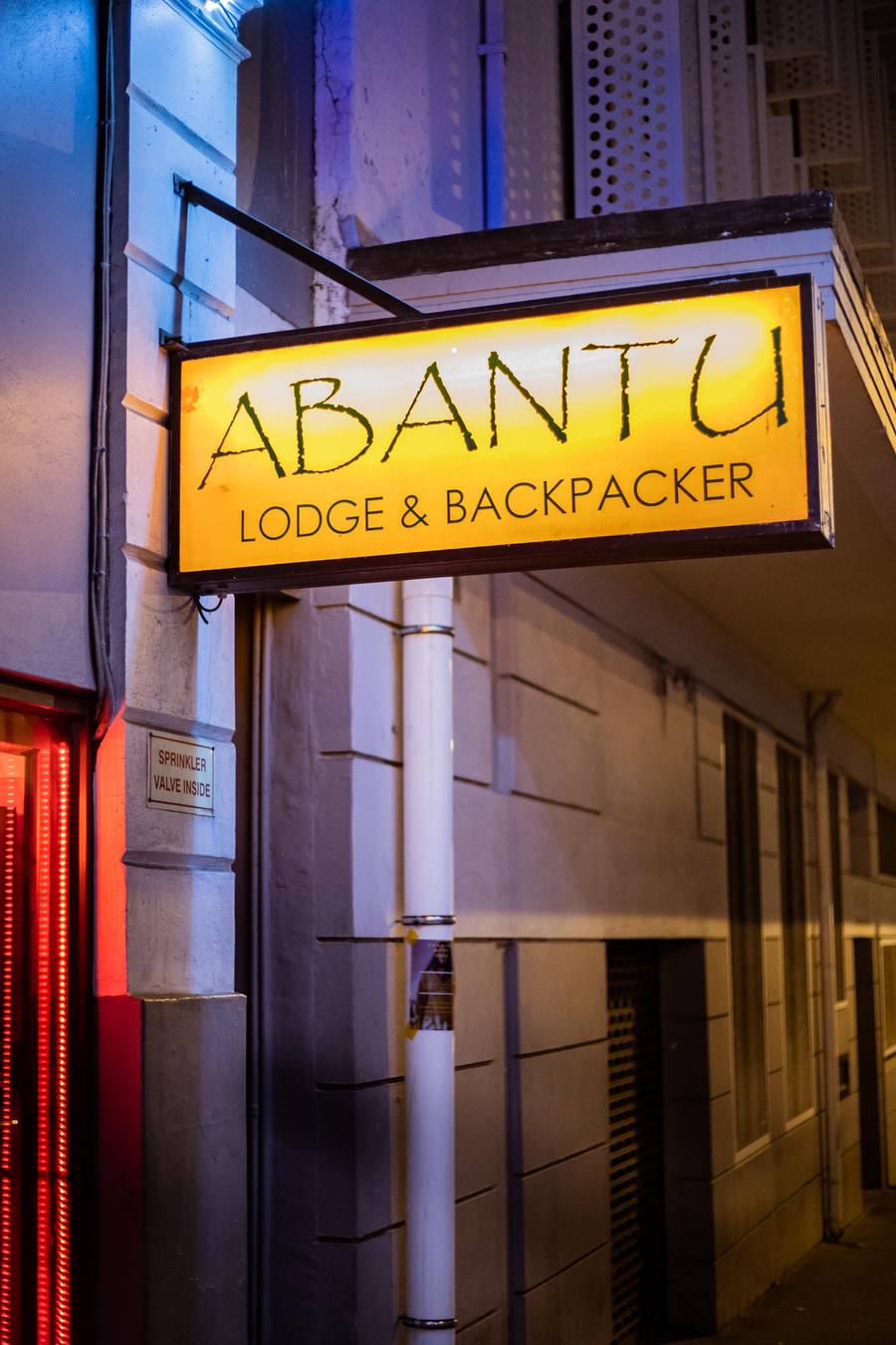 Yellow sign for Abantu Lodge & Backpacker hangs above a building