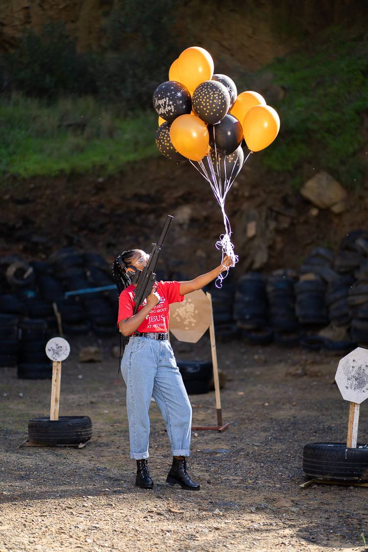 A woman holding a gun and balloons in a shooting range