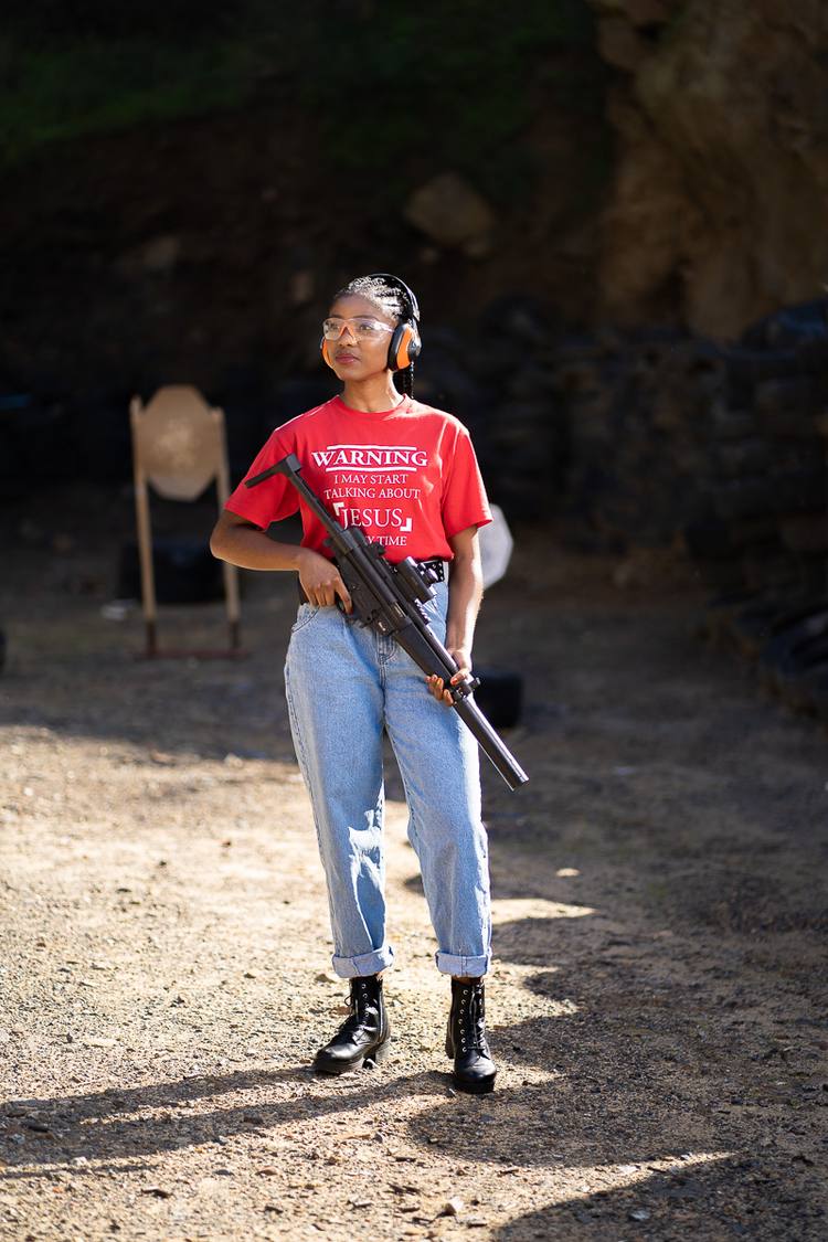 Woman with rifle at shooting range, wearing protective goggles and headphones
