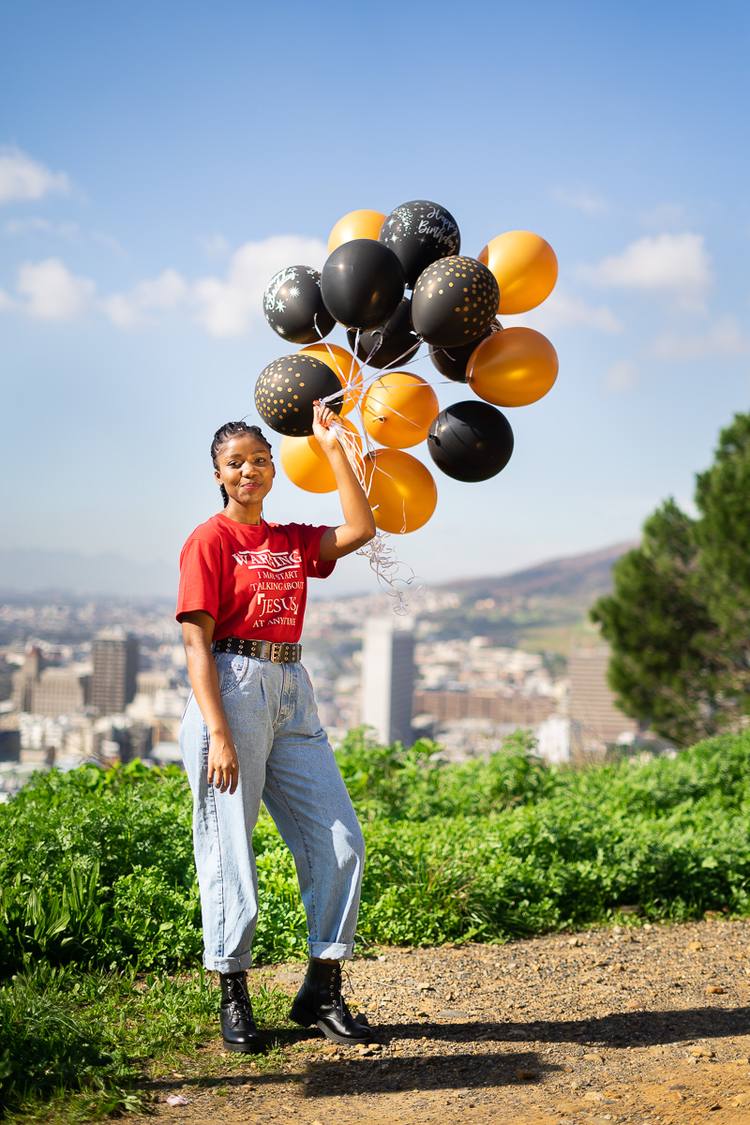 Woman holding a bunch of balloons in a scenic outdoor setting