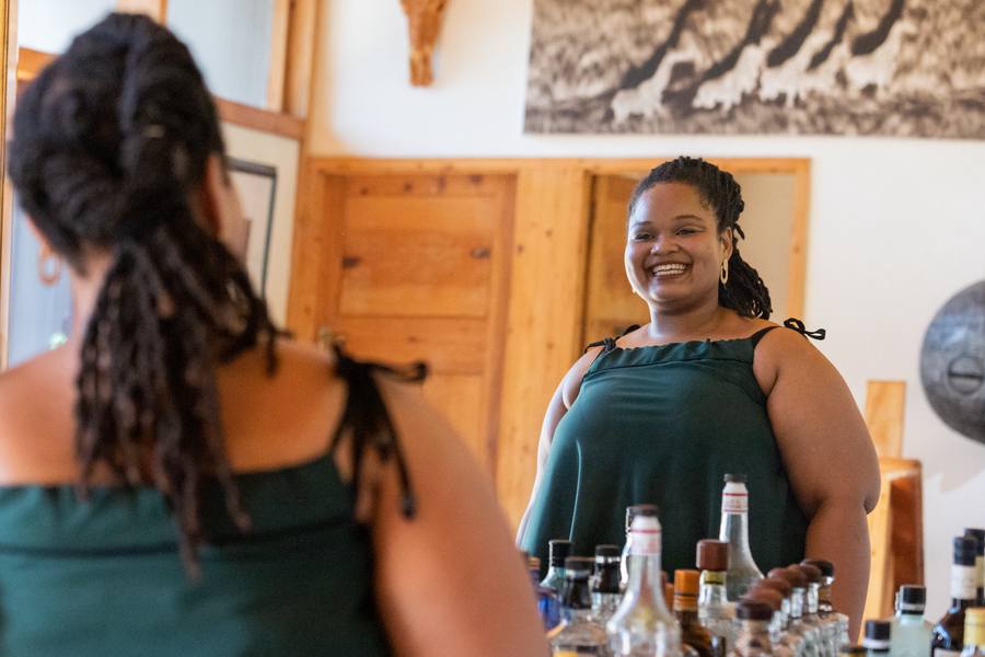 Two women in green dresses smiling at each other with bottles of alcohol in the foreground