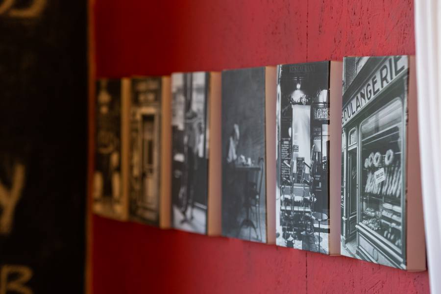 A row of black and white photographs on a red wall