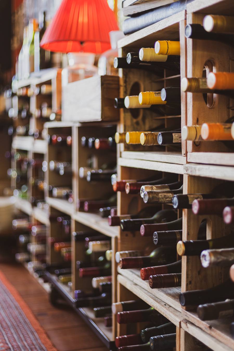Wooden wine racks filled with bottles, lit by a red lamp
