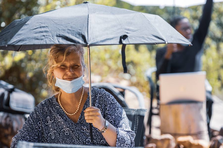 Woman with face mask holding umbrella, another person in background