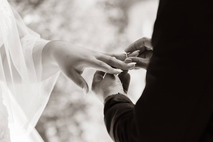 A groom places a ring on a bride's finger during a wedding ceremony.