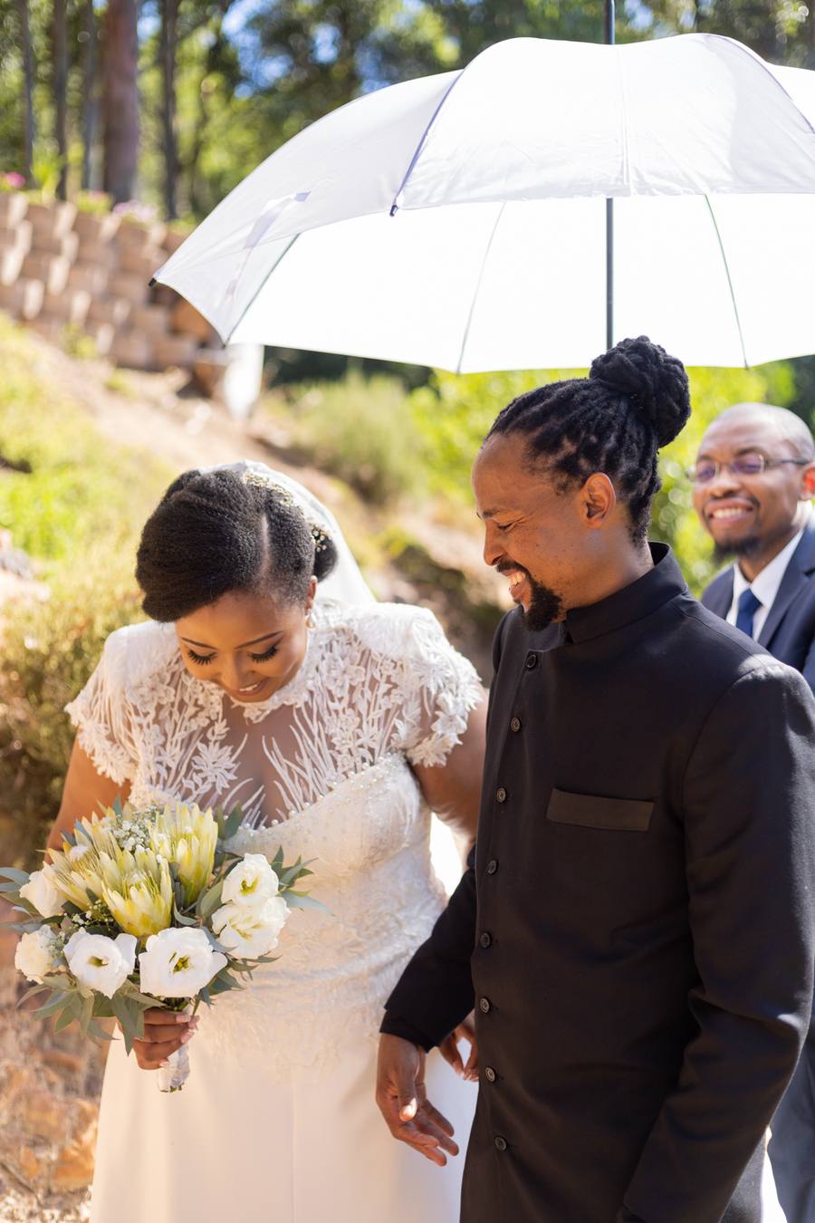 Bride and groom smiling at each other with umbrella overhead