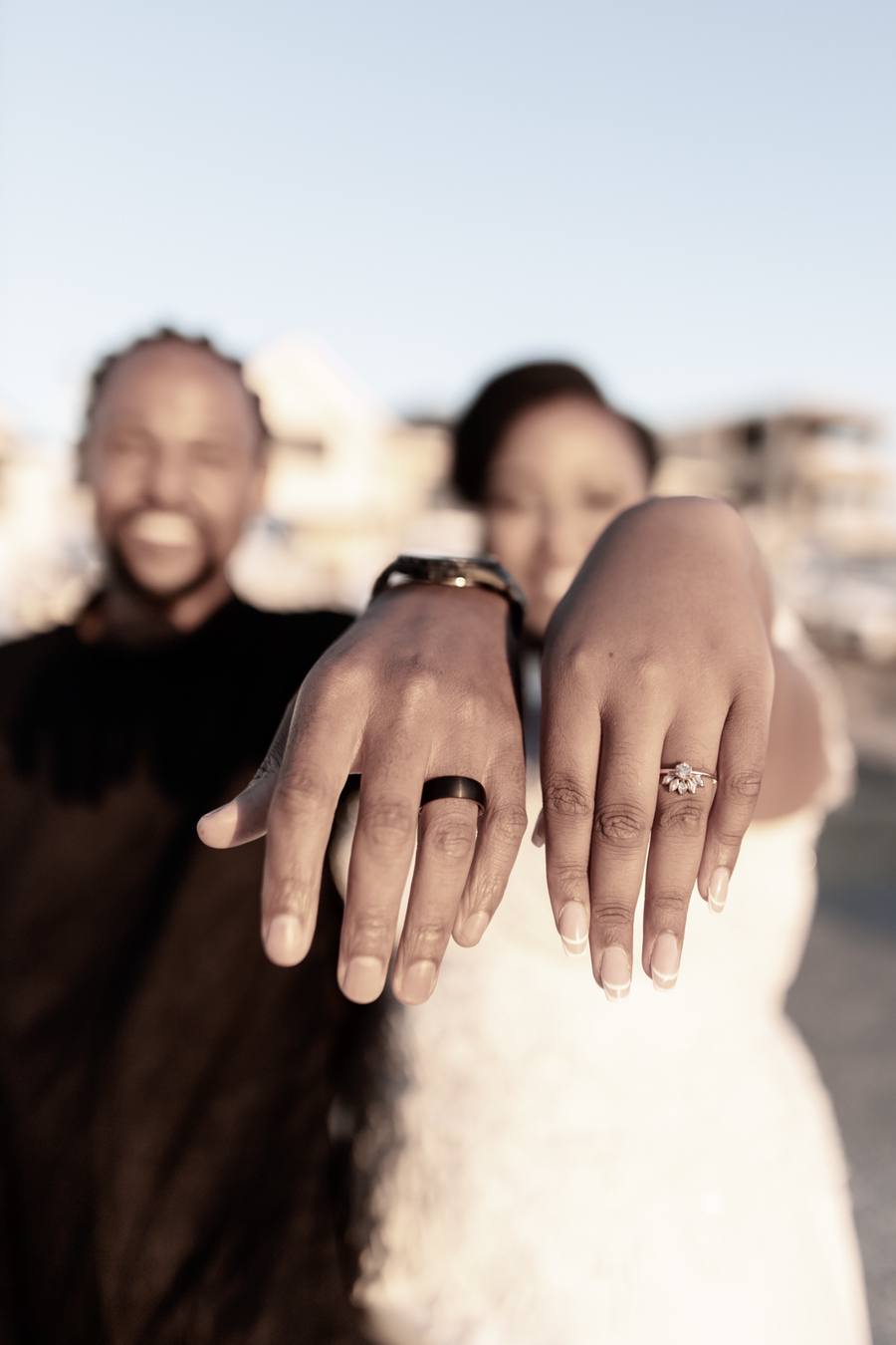 A man and woman hold hands with wedding rings visible on their fingers