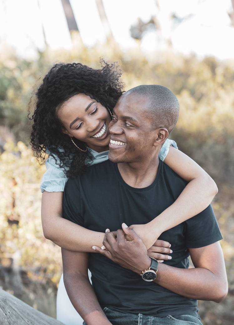 A smiling couple embracing each other in a natural setting