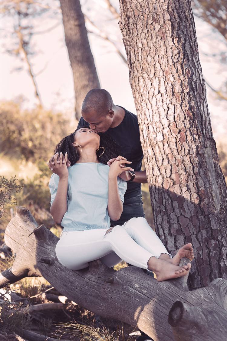 Couple sitting on a tree branch, woman looking up at man