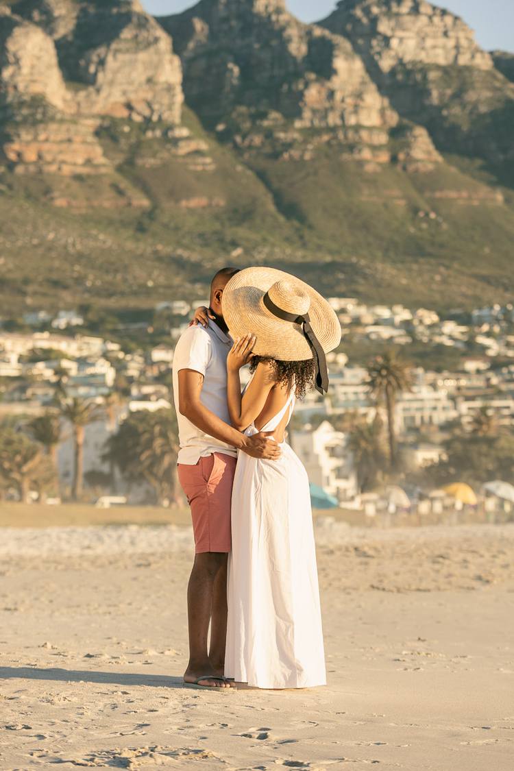 Couple embracing on beach with mountains in the background