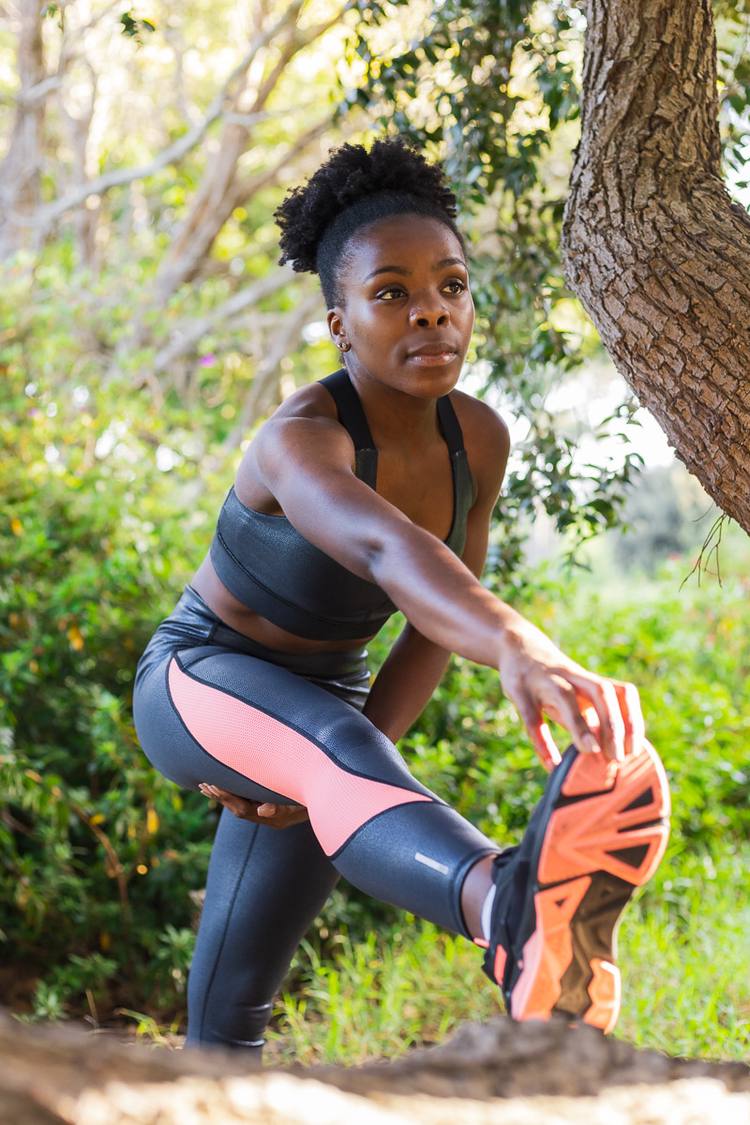 Woman in workout gear stretching leg muscles in a park