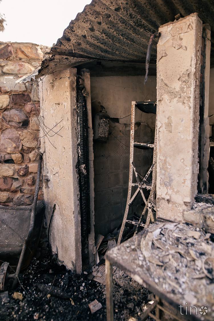 Charred remains of a building with a ladder and stone wall