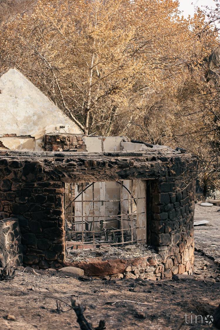 Stone structure with a metal gate, burnt and surrounded by trees