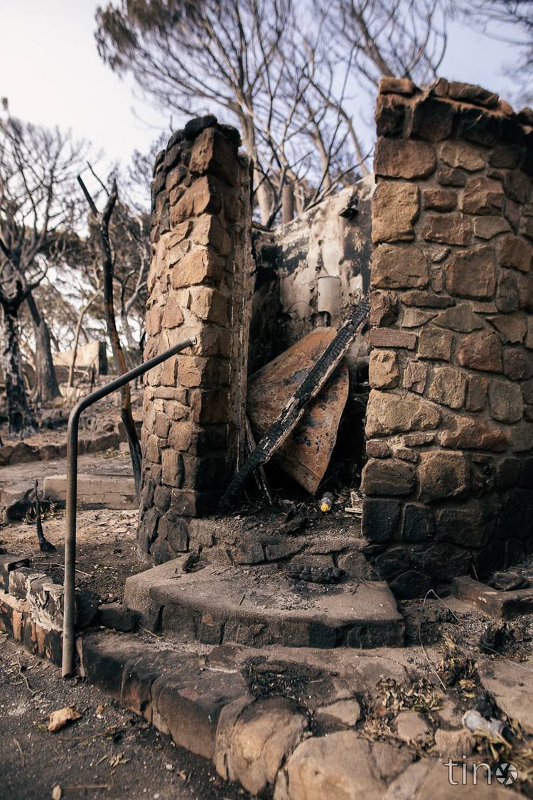 Charred stone pillars and steps with a burnt handrail and debris