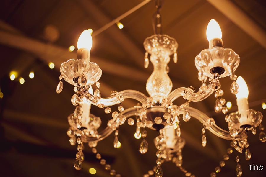 A chandelier with crystal pendants hanging from a ceiling, illuminated by warm light.