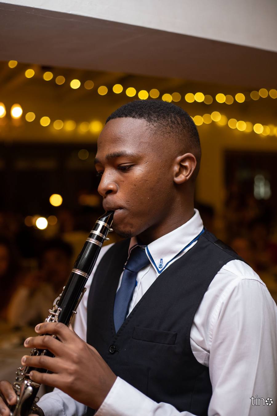 A young man plays a clarinet at a formal event.