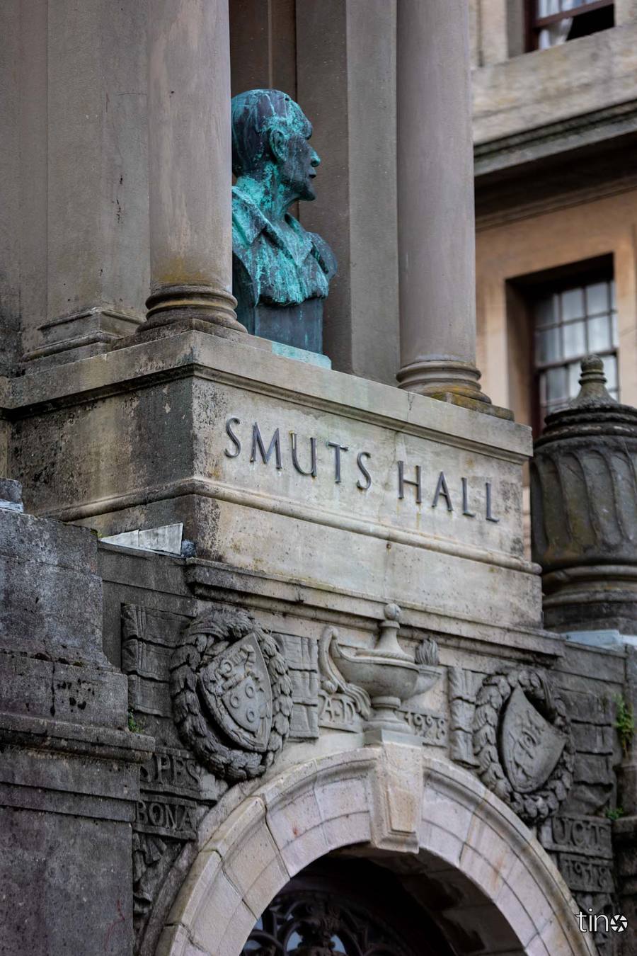 A bronze bust of a man sits between two columns above the entrance to Smuts Hall