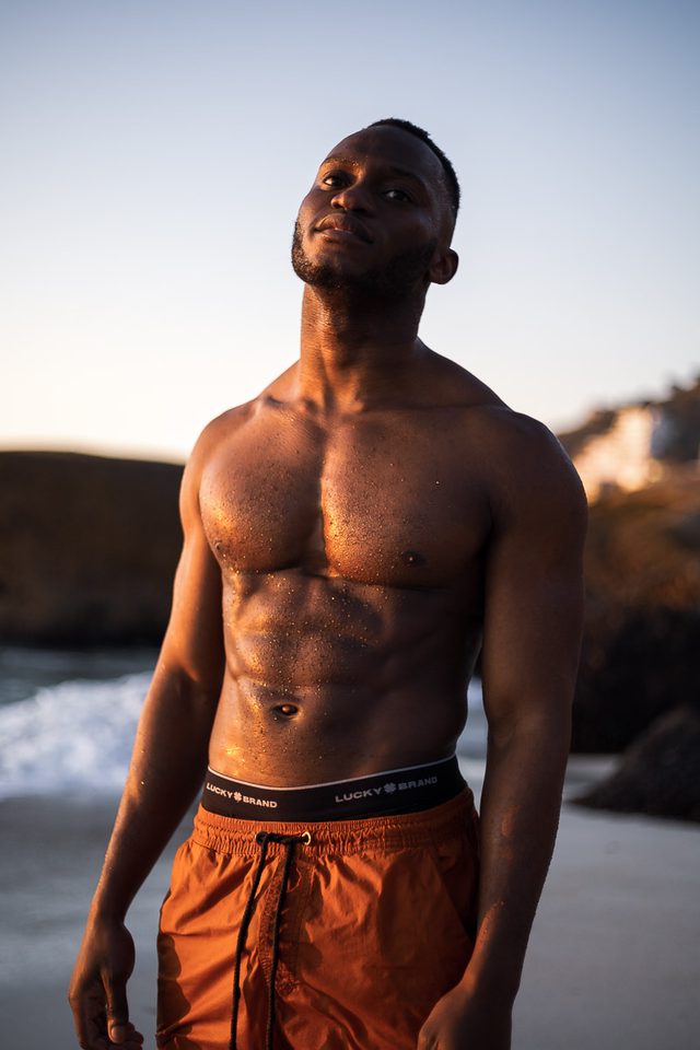 Man standing on beach with orange shorts and black waistband