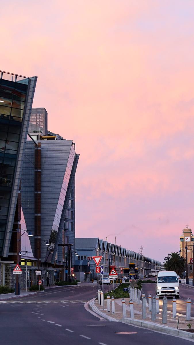 A street with a van and buildings under a pink sky