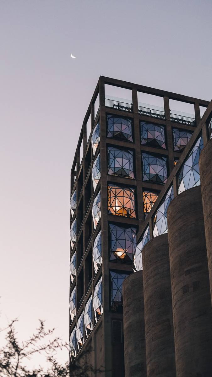 A modern building with a glass facade and a crescent moon in the sky