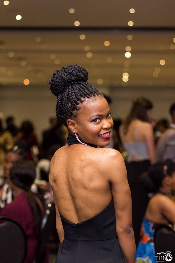 Woman with braided bun hairstyle, back view, smiling at a crowded event