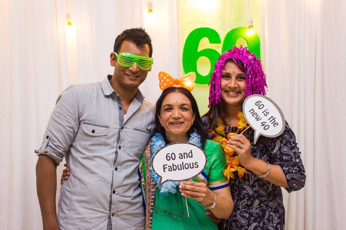 Three people pose for a photo with speech bubbles reading '60 and Fabulous' and '60 is the new 40
